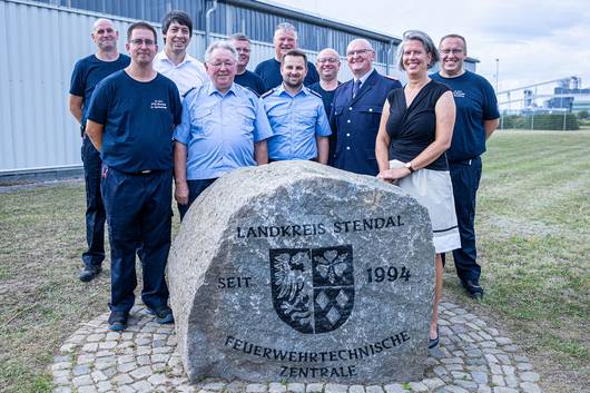 Zum 25-jährigen Bestehen erhielt die FTZ einen Gedenkstein, um den sich das Team zusammen mit Landrat Patrick Puhlmann, den Kreisbrandmeisterin seit Gründung sowie Tamara Zischang zum Erinnerungsfoto versammelt hat.